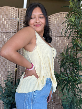 Cream waffle-knit sleeveless halter top with button front and high-low hem.
