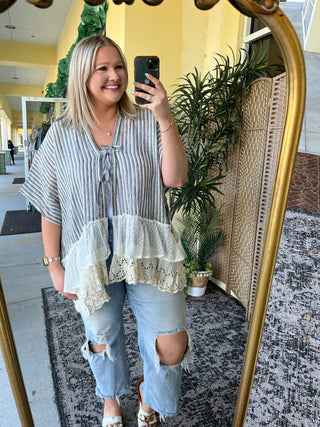 Black and white striped kimono top with white ruffled lace hem, worn with distressed light wash jeans.
