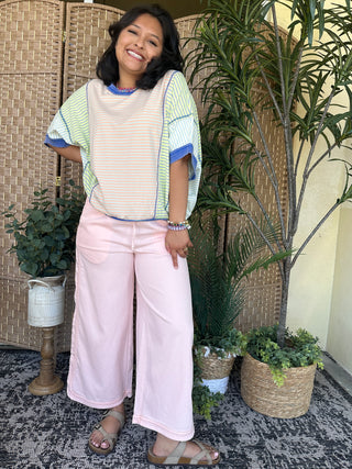 Light pink wide-leg denim pants with relaxed fit and full-length silhouette.
