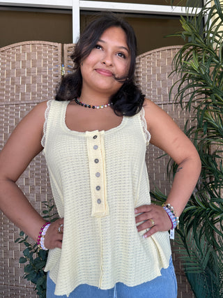 Cream ribbed sleeveless tank top with button placket and lace trim details.
