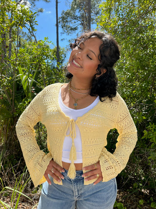 Lemon yellow knit cardigan with tie-front closure and tassel detail over white tank top.
