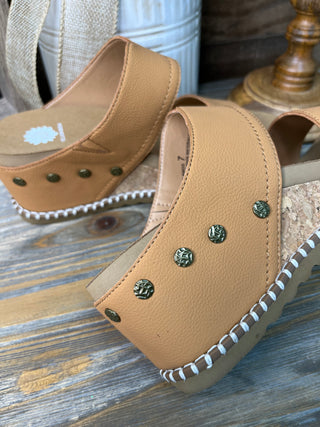 Tan leather wedge sandals with decorative studs and white stitching detail.
