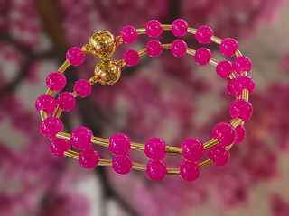 Hot pink glass bead bracelet with gold spacers and magnetic closure on floral background.
