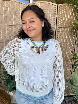 White open-knit crochet long-sleeve top with turquoise trim and contrasting ribbed hem.
