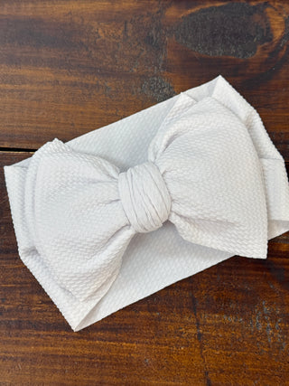 White oversized headband bow for baby girls, perfect for adding a cute and stylish touch to any infant's outfit.