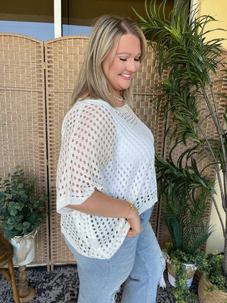 White crochet dolman top with openwork pattern and short sleeves.
