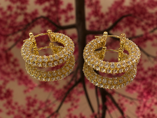 Gold diamond hoop earrings with layered curved design and crystal embellishments.
