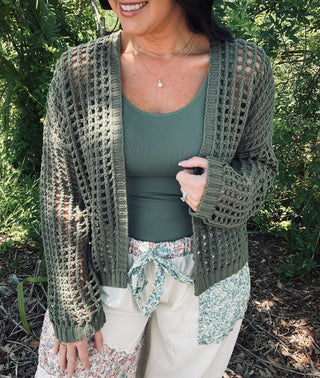 Doe & Rae crochet open weave cropped cardigan in cream and black colors, displayed on a hanger against a soft beige background.