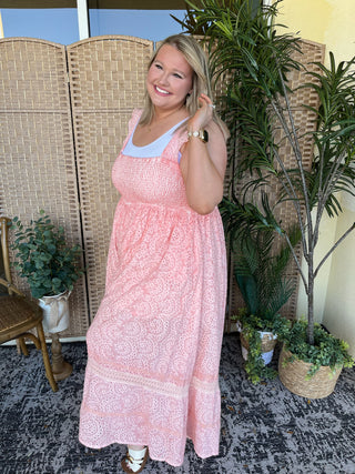 Pink eyelet sleeveless jumpsuit with white trim neckline and smocked bodice detail.
