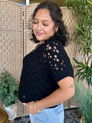 Black open weave short-sleeve sweater with crochet texture and cutout details.
