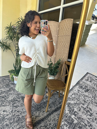 Olive green Bermuda shorts with drawstring waist, paired with white ribbed top.
