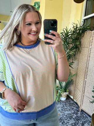 Oversized striped dolman top in coral, orange, and blue stripes with blue ribbed trim.
