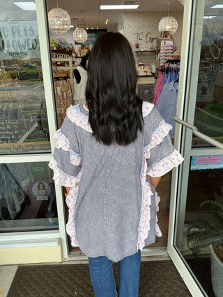 Oli & Hali Lavender & Blue Stripe Ruffle Top on Display Against Soft Pink Background