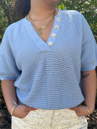 Sky blue textured knit short-sleeve V-neck top with pearl button placket detail.
