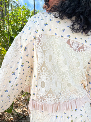Cream button-down top with blue cornflower floral print and white lace eyelet overlay panel.
