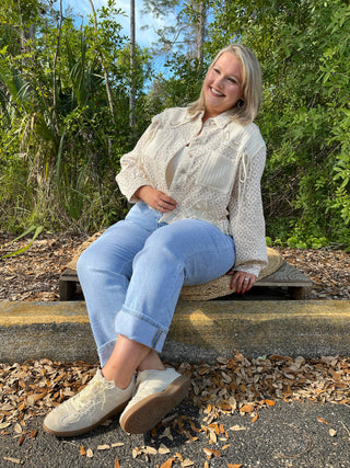Cream floral button-up jacket with textured fabric and sheer sleeves paired with light blue jeans.
