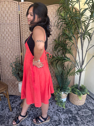 Bright red denim halter romper with black contrast yoke and adjustable straps, knee-length silhouette.
