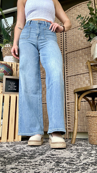Light wash high-rise wide-leg jeans with patch pockets, paired with cream platform shoes.
