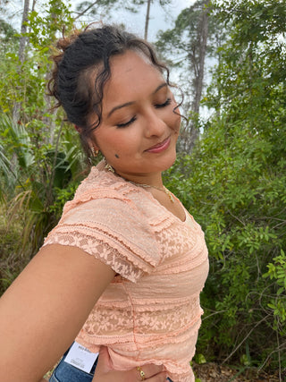 Peach lace short-sleeve top with textured crochet pattern and ruched detailing.
