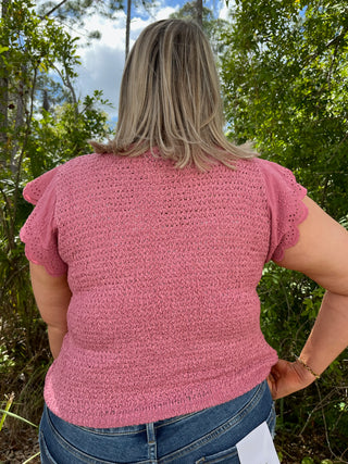 Pink short-sleeve top with textured fabric and eyelet ruffle trim on sleeves.
