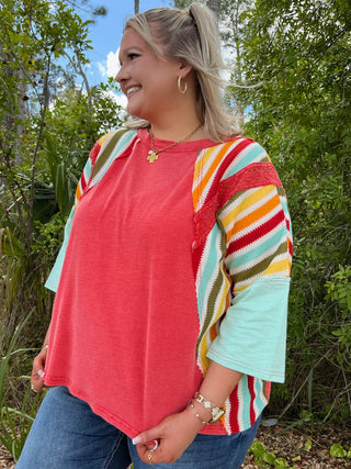 Red mineral wash top with multicolor striped three-quarter sleeves in mint, yellow, orange and red.
