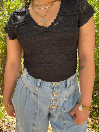 Black lace cap-sleeve top with V-neckline and textured lace panels.
