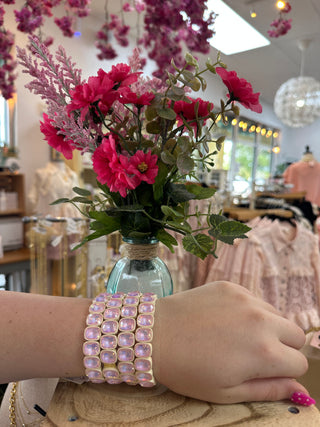 Multi-strand stretch bracelet with soft pink square gemstones worn on wrist.