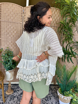 Cream and mauve striped short-sleeve top with white eyelet ruffle hem and lace trim detail.

