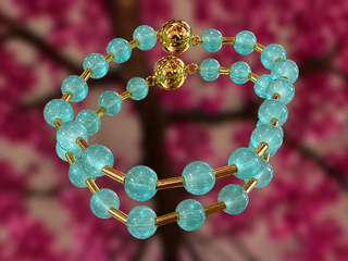 Turquoise glass bead magnetic bracelet with gold-tone spacers and decorative beads on pink floral background.
