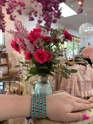 Mint green stretch bracelet with hot pink square gemstones worn on wrist.