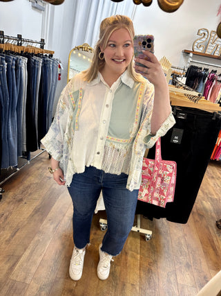 Cream oversized button-down shirt with blue and gold paisley print, worn with dark wash cropped jeans.
