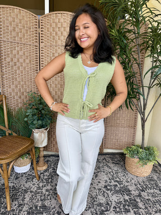 Green apple waffle knit cardigan vest with tie front and white pants.
