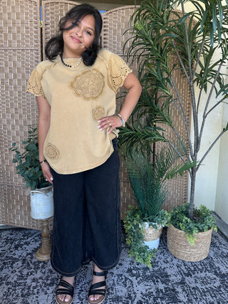 Cream oversized tee with crochet circle appliqués and eyelet sleeves.

