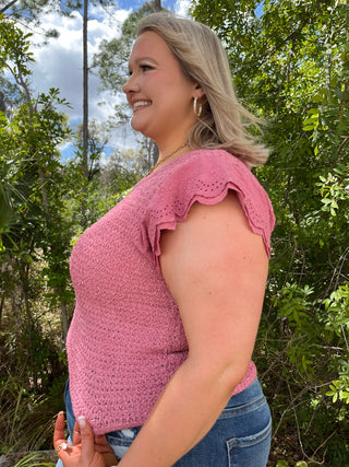 Pink textured short-sleeve top with eyelet ruffle cap sleeves and scalloped neckline detail.
