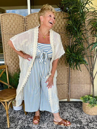 Blue and white striped strapless jumpsuit with tie-front detail and cream linen short-sleeve shirt.
