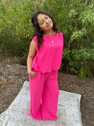 Hot pink sleeveless top and wide-leg pant set with textured fabric, modeled outdoors.
