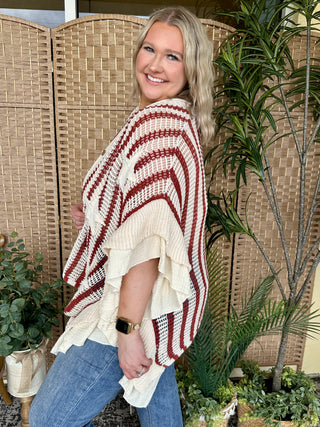 Red and cream striped knit poncho with waffle texture and asymmetrical hem.
