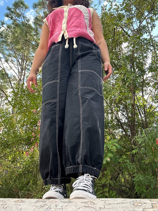 Black jogger pants with white contrast stitching and drawstring waistband, paired with pink quilted vest.
