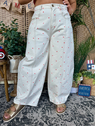 Ivory wide-leg denim pants with red polka dot pattern and high-waisted gypsy fit.
