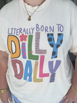 White t-shirt with colorful "Literally Born to Dilly Dally" text and patterned letters in various colors.
