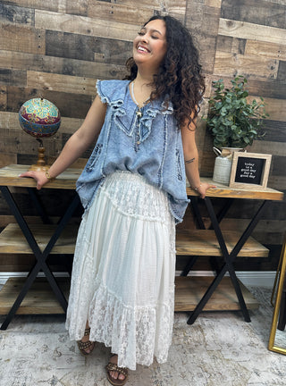 Light blue denim sleeveless top with ruffled collar and tie front detail.
