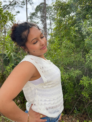 White crochet sleeveless tank top with textured knit pattern and distressed details.
