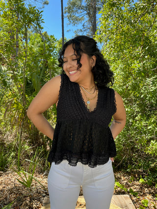 Black lace v-neck sleeveless top with scalloped hem and textured fabric detail.
