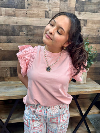 Blush pink sleeveless top with eyelet flutter sleeves and crew neckline.
