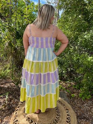Tiered maxi dress in purple, blue, and lime geometric striped pattern with crochet trim details.

