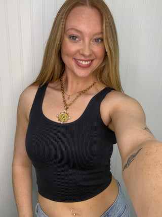 Black ribbed sleeveless tank top with scoop neckline on model.
