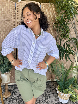 Lavender pinstripe boho oxford shirt with white trim and rolled sleeves paired with sage green shorts.
