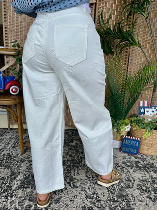 White gypsy fit pants with textured dot pattern and five-pocket design.
