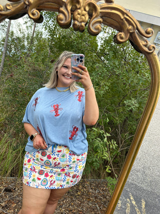 Light blue tee with red sequin lobster graphics scattered across front.
