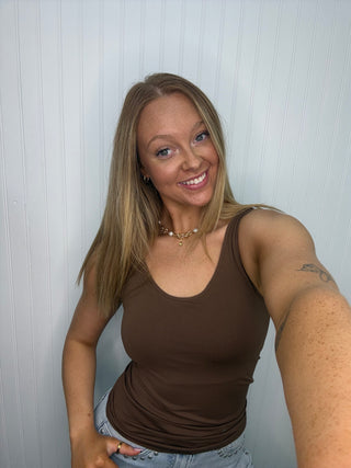 Brown seamless tank top with built-in bra, scoop neckline, worn with light blue jeans.
